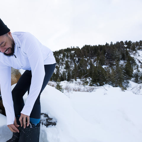 Man preparing for outdoor winter activities in men's thermal base layers from Hot Chillys in snowy landscape
