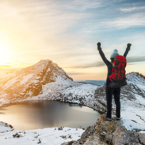 Woman celebrating in nature while wearing womens thermal base layers with a stunning snowy landscape in the background