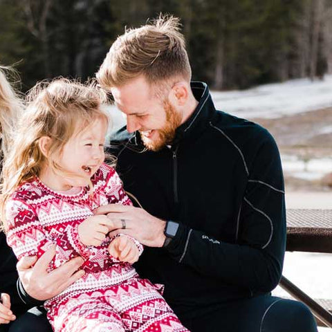 Family enjoying winter fun in Hot Chillys kids thermal base layers for warmth and comfort outdoors