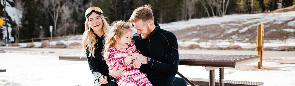 Family enjoying winter fun in Hot Chillys kids thermal base layers for warmth and comfort outdoors
