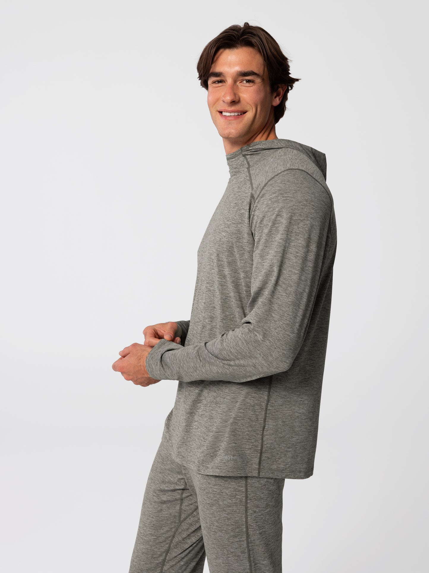 Man wearing Hot Chillys Clima-Tek hoodie and bottom base layer set in dark olive, side view