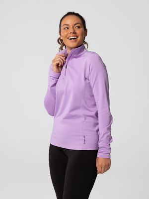 Side view of woman wearing Hot Chillys Micro-Elite Chamois Zip-T in light lavender with matching black tights