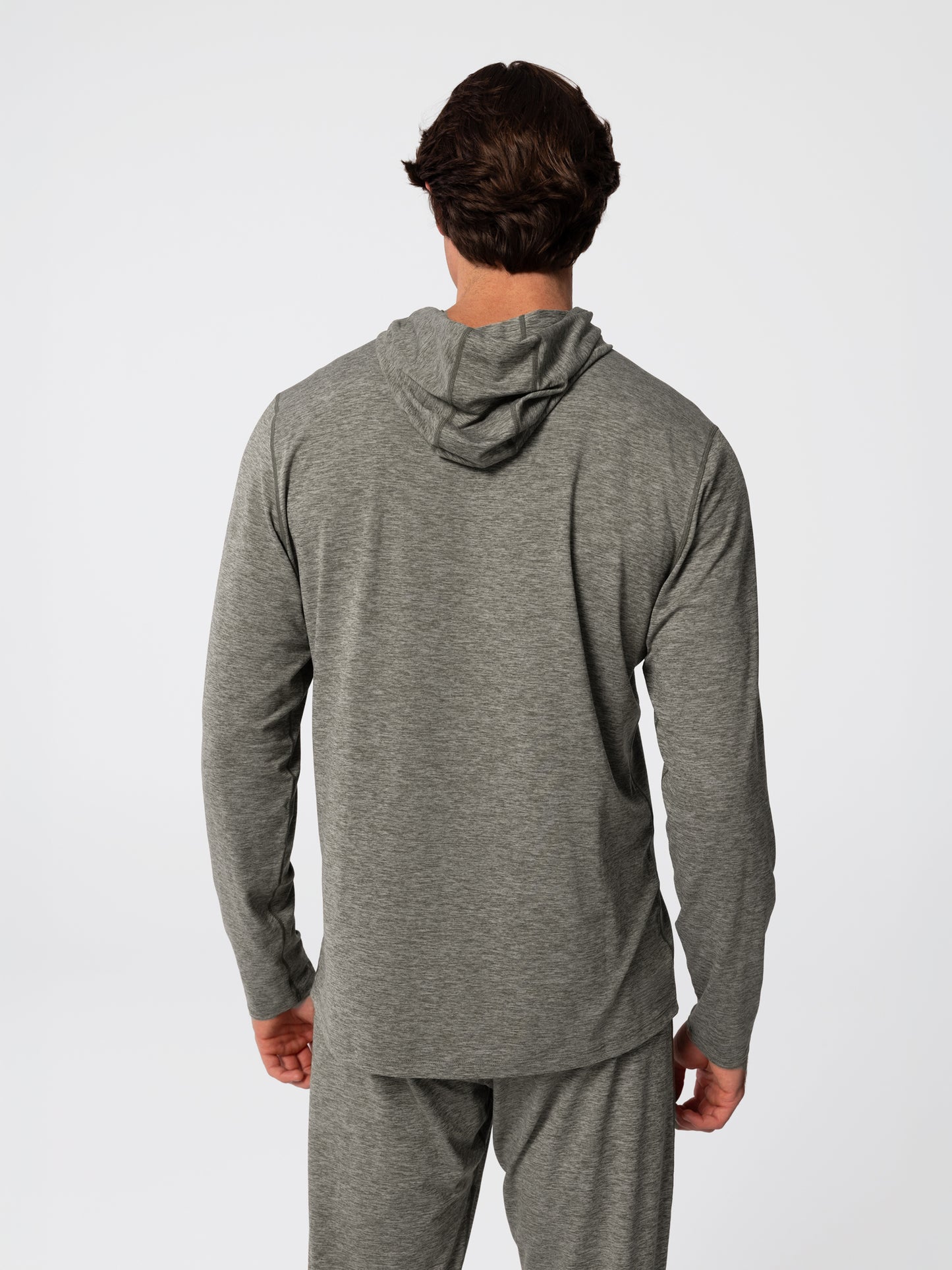 Man wearing Hot Chillys Clima-Tek hoodie and bottom base layer set in dark olive, back view