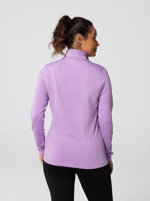 Back view of woman wearing Hot Chillys Micro-Elite Chamois Zip-T in light lavender with matching black tights