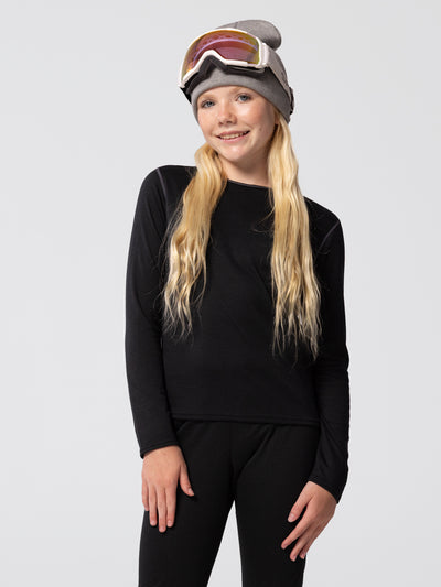 Youth wearing Hot Chillys Pepper Bi-Ply black thermal crewneck top and matching bottoms, with a beanie and ski goggles