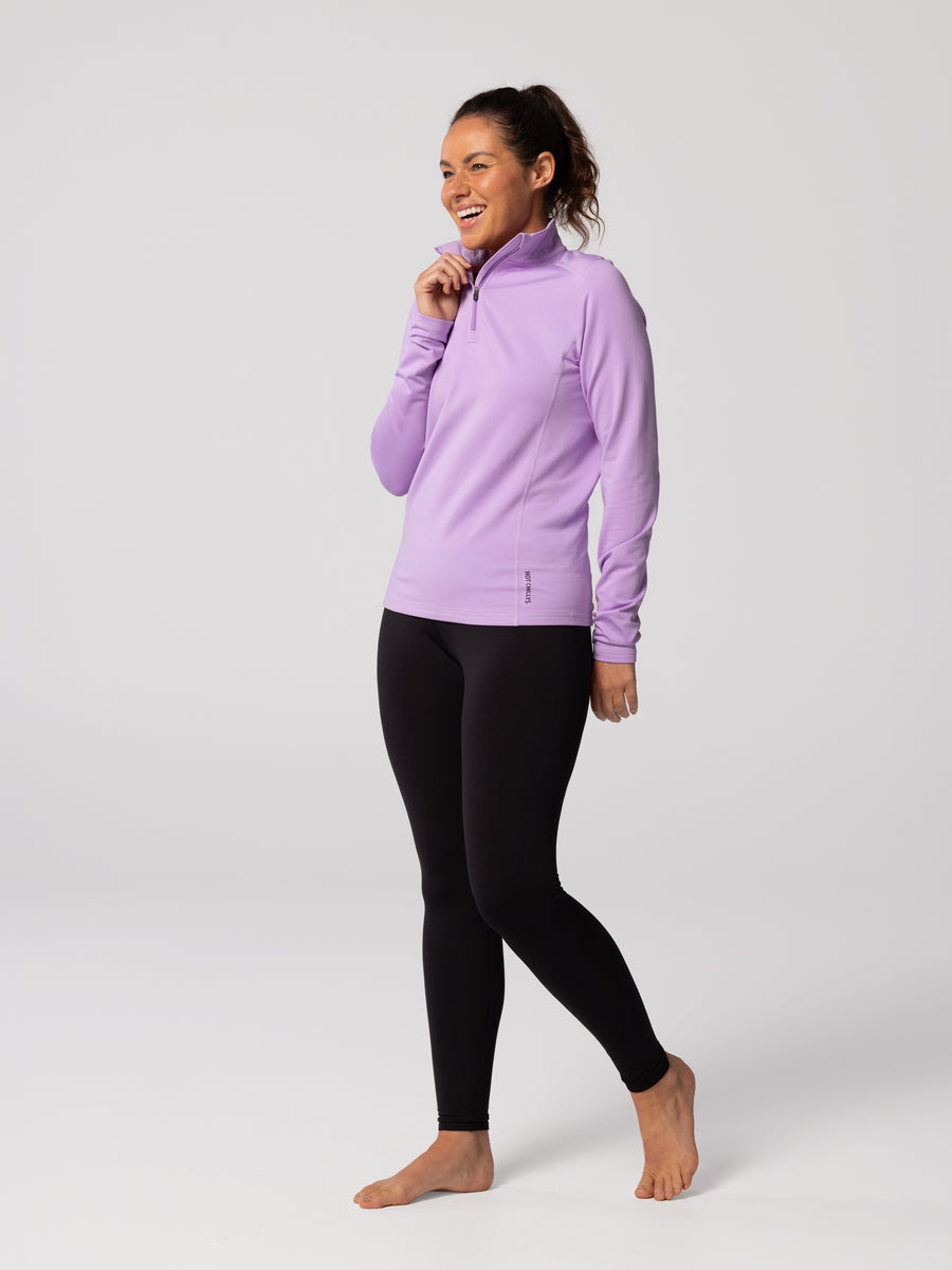 Full-body view of woman wearing Hot Chillys Micro-Elite Chamois Zip-T in light lavender with matching black tights