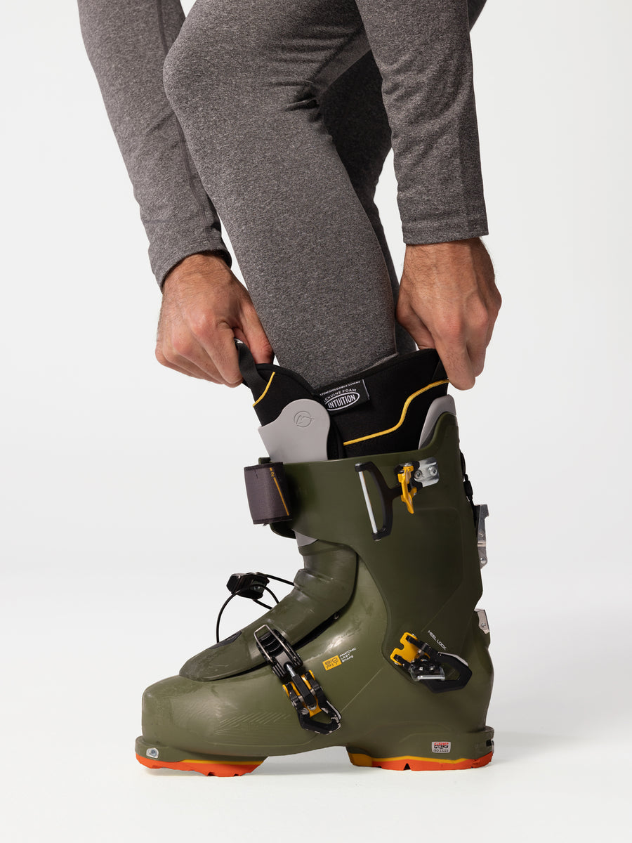 Detail view of man's leg wearing Hot Chillys Micro-Elite Chamois granite thermal tights while putting on a ski boot