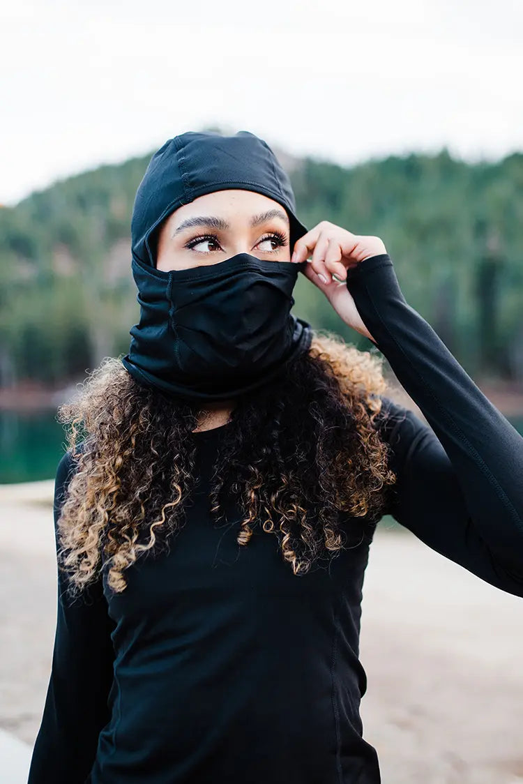 Woman wearing Hot Chilly winter sport mask with a tree covered mountain in the background