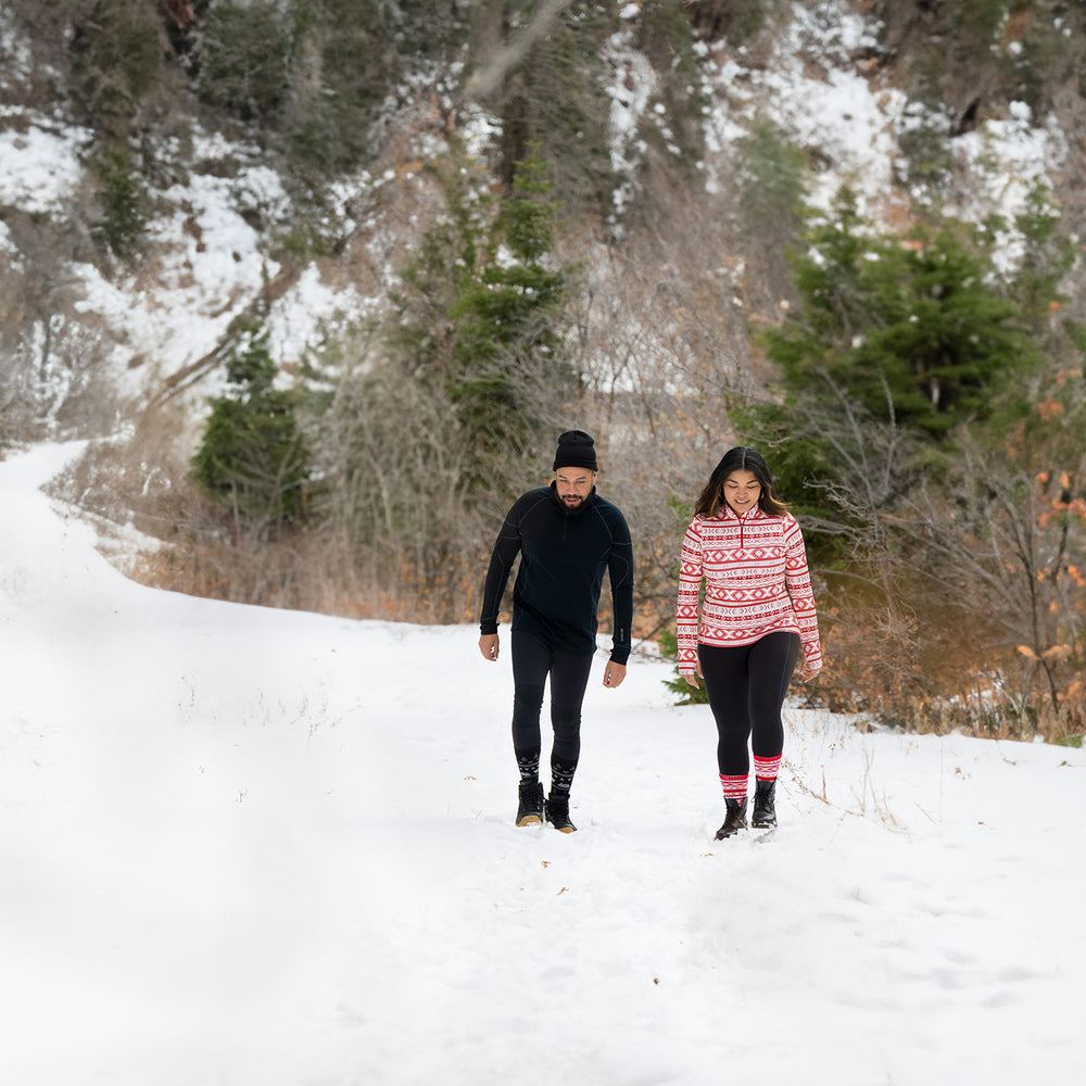 Two people wearing Hot Chillys Base Layers hiking up a snowy mountain road