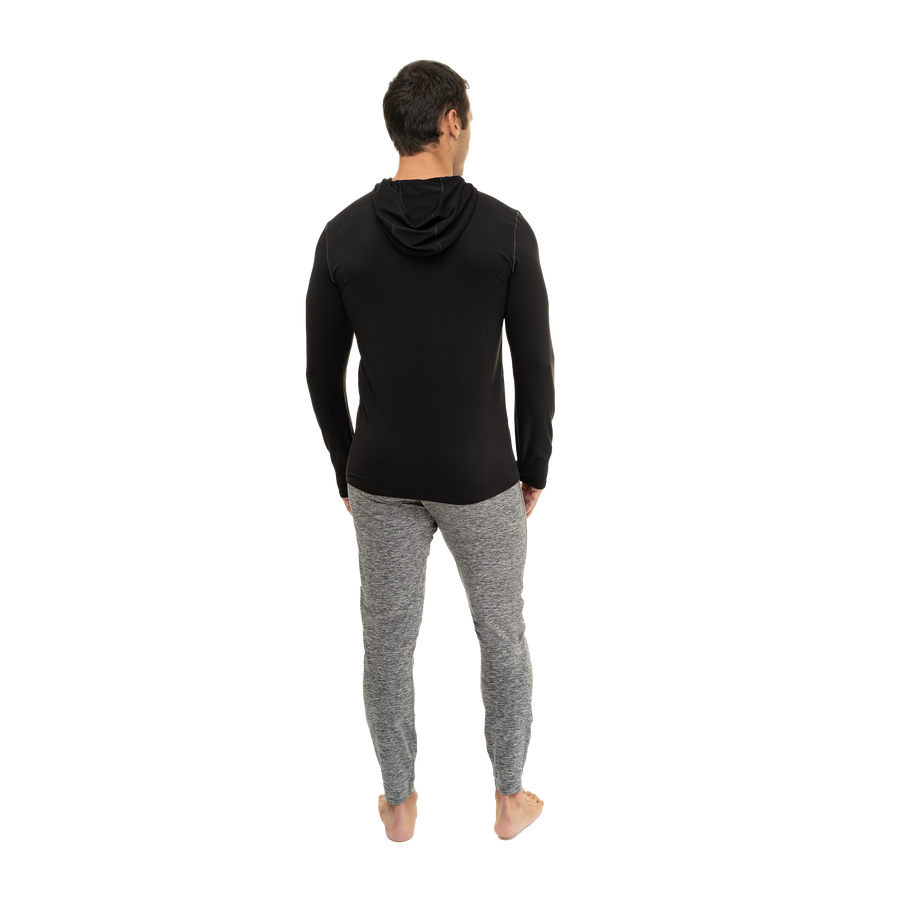 Back view of a man wearing Hot Chillys men's winter thermal hoodie in black with gray pants